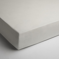 Matras met ivoorkleurig hoeslaken, waarbij de kleur en textuur goed te zien zijn.