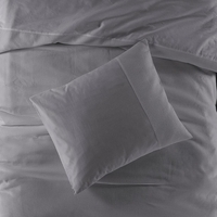 Een comfortabel bed met een grijze dekbed en kussens, perfect voor ontspanning en slaap.