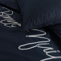 Donkerblauw bed met witte letters op het overtrek, die een moderne en stijlvolle uitstraling geven aan de slaapkamer.