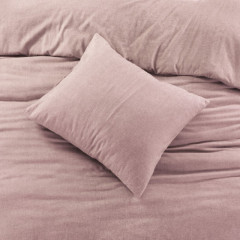 Een bed met een zacht roze dekbed en kussen, perfect voor een comfortabele en stijlvolle slaapkamer.