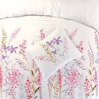 Een bed met witte beddengoed en een vrolijk bloemenkussen, dat comfort en stijl combineert.