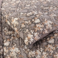 Een bed met een vrolijke bloemenprint op het dekbed, perfect voor een frisse en levendige slaapkamerinrichting.