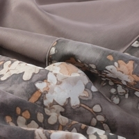 Close-up van een beige en wit bloemenpatroon op stof, met een elegant en verfijnd ontwerp.