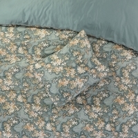 Een groen dekbed met een bloemenprint ligt op een bed, wat een frisse en vrolijke sfeer in de slaapkamer creëert.