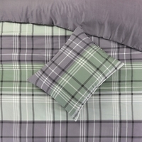 Groene en grijze geruite dekbed met bijpassend kussen op een bed.