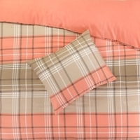 Een bed met een geruit dekbed en een oranje kussen, dat een warme en gezellige uitstraling heeft.