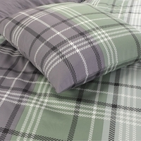 Een bed met een dekbed in groen en grijs, dat een warme en comfortabele uitstraling geeft aan de slaapkamer.