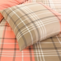 Een bed met een geruit en een oranje kussen, die samen een stijlvol en comfortabel slaapdecor vormen.