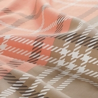 Detailopname van een geruite stof in oranje en wit, met een levendig en speels ontwerp.