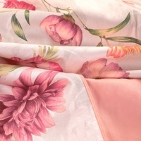 Close-up van een beddengoed met een roze en grijze bloemenprint, perfect voor een frisse en vrolijke slaapkamerlook.