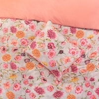 Een bed met een vrolijk bloemenmotief en een schattig bijpassend kussen, ideaal voor een warme en sfeervolle inrichting.