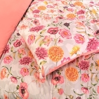 Een bed met een vrolijk bloemenmotief en een bijpassend kussen, ideaal voor een warme en sfeervolle inrichting.