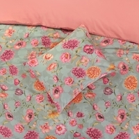 Een bed met een vrolijk bloemenmotief en een bijpassend kussen, ideaal voor een warme en sfeervolle inrichting.