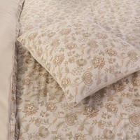 Een bed met een fris beige dekbed en kussen, perfect voor ontspanning en een goede nachtrust.