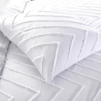 Een wit bed met een wit kussen en een chevronpatroon, dat elegantie en eenvoud uitstraalt in de slaapkamerinrichting.