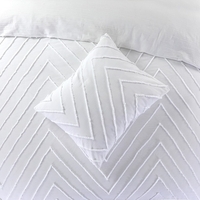 Een wit bed met een wit kussen en twee extra kussens, alles in een rustige en serene slaapkameromgeving.