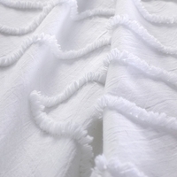 Witte stof met franjes, die een zachte en textuurrijke uitstraling heeft.