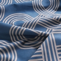 Close-up van een geometrisch patroon in blauw en wit op een bedsprei, dat een stijlvol accent geeft aan de slaapkamerinrichting.