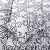 Een opgemaakt bed met een dekbed in wit en grijs patroon, met kussens die een gezellige sfeer creëren.