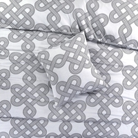 Een bed met een comfortabel wit en grijs patroon dekbed, met kussens die uitnodigen om te ontspannen.