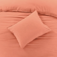 Een bed met een oranje kussen, dat een vleugje kleur en warmte toevoegt aan de slaapkamer.