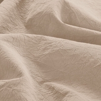 Close-up van een zacht zandkleurig beddengoed, dat een warme en uitnodigende sfeer uitstraalt.