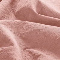 Close-up van een roze laken met een lichtroze stof, die een zachte en delicate uitstraling heeft.