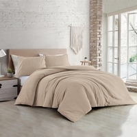 Een zandkleurige dekbedovertrekset ligt op een wit bed, wat zorgt voor een rustige en comfortabele sfeer in de slaapkamer.