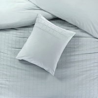 Een eenvoudig bed met twee kussens en een lichtgroen dekbed, perfect voor een ontspannen slaapomgeving.