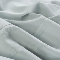 Close-up van een lichtgroen beddengoed, dat een kalme en comfortabele sfeer uitstraalt.