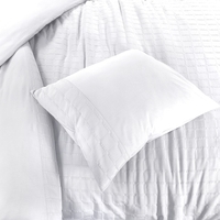 Een opgemaakt wit bed met zachte kussens en een witte dekbed, stralend in een serene slaapkamer.