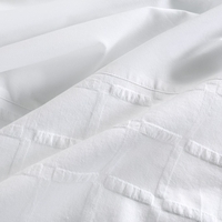 Close-up van een wit bed met een frisse, witte dekbedhoes die een serene en schone uitstraling geeft.