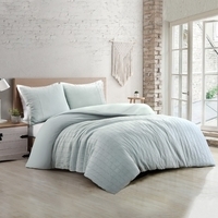 Slaapkamer met een eenvoudig lichtgroen bed en een raam dat de ruimte verlicht met daglicht.