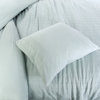 Een bed met twee kussens en een lichtgroene dekbed, een serene en gezellige plek om te ontspannen en te slapen.