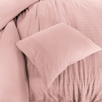 Een bed met een schattig roze dekbed en kussen, dat een vrolijke en rustgevende uitstraling heeft.