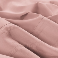 Detailopname van een roze laken met een gevouwen rand, dat een warme en comfortabele sfeer uitstraalt.