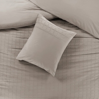 Een bed met een kussen en een zandkleurig dekbed, een gezellige en comfortabele plek om te slapen.