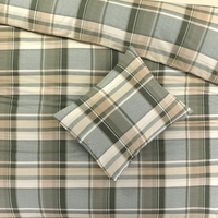 Een bed met een geruite dekbed en kussen, dat een gezellige en uitnodigende sfeer uitstraalt.