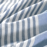 Close-up van een stof met blauwe en witte strepen, die een levendig en textuurrijk patroon toont.