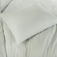 Een kussen op een bed met een groene dekbedhoes, dat een rustgevende en comfortabele sfeer uitstraalt.