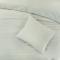 Een eenvoudig bed met een lichtgroene hoes en een kussen, dat een rustige en comfortabele slaapomgeving biedt.