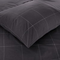 Close-up van een kussen op zwart geblokte lakens, met een gezellige en moderne uitstraling.