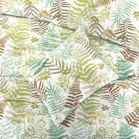 Een bed met een groen en bruin varenpatroon, dat een natuurlijke en rustgevende sfeer creëert in de slaapkamer.