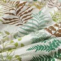 Een bed met een bladprint in groen en bruin, perfect voor een frisse en organische uitstraling in de slaapkamer.