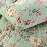 Een bed bedekt met een groen bloemenpatroon, dat een vrolijke en uitnodigende ambiance aan de slaapkamer toevoegt.