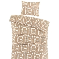 Een bed met een elegant wit en beige patroon op het dekbed, dat een warme en gezellige sfeer uitstraalt.