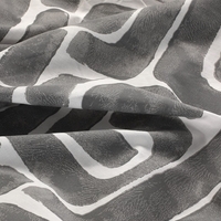 Detailopname van een grijs-wit geweven stof met een mooi, complex patroon.