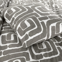 Een bed met een grijs en wit patroon dekbed, dat een gezellige en moderne uitstraling heeft.