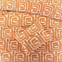 Een oranje en witte dekbed met geometrische patronen, dat een moderne en gezellige uitstraling aan de slaapkamer geeft.