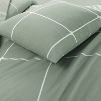 Groene bed met witte kussens en een wit ruitpatroon, ideaal voor een stijlvolle en rustgevende slaapkamer.